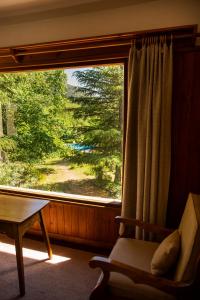 a room with a window with a chair and a table at Hotel Las Cascadas in La Cumbrecita +113 photos