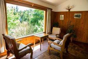 a room with a table and chairs and a large window at Hotel Las Cascadas in La Cumbrecita