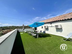 eine Terrasse mit einem Tisch und einem Sonnenschirm auf dem Dach in der Unterkunft Le gite aux oliviers in Laredorte