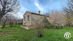 een oud stenen huis in een veld met bomen bij L'esquirou in Lagarrigue