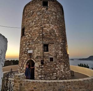 a woman standing in the doorway of a stone tower at Casa Milos Windmill Alonissos in Alonnisos