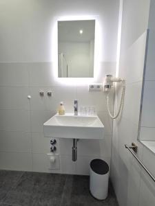 een witte badkamer met een wastafel en een spiegel bij Hotel Spreeufer in Lübben +30 foto's