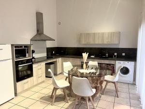 eine Küche mit einem Glastisch und weißen Stühlen in der Unterkunft Domaine des Étoiles - Gîtes in Gillonnay