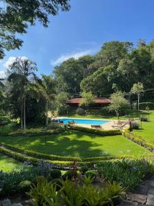 a view of a garden with a swimming pool at Pousada Tucano Do Cuiabá in Itaipava