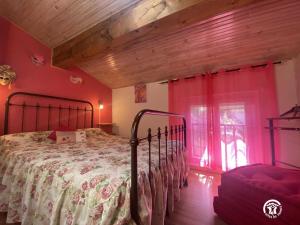 een slaapkamer met een bed met roze muren en een raam bij Le moulin in Sahorre