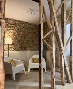 a living room with two chairs and a stone wall at Maison boutet 9 in Fanjeaux