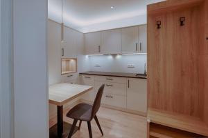 a kitchen with white cabinets and a table and a chair at ADAM Suites - Brixen Card included in Bressanone