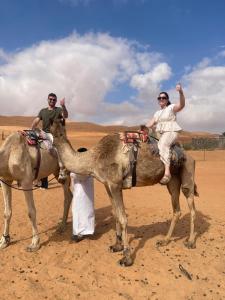 two men riding on the back of a camel at ESCAPE cAMp2 in Bidiyah +26 photos