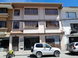 een witte truck geparkeerd voor een gebouw bij Departamento in Cuenca