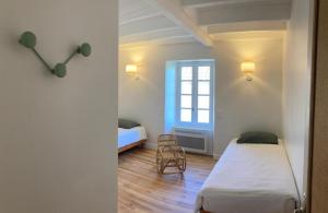 een kleine kamer met twee bedden en een raam bij Chez denise in Paulinet