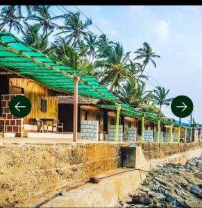 a building on the beach with palm trees in the background at Sea View Cottages in Arambol