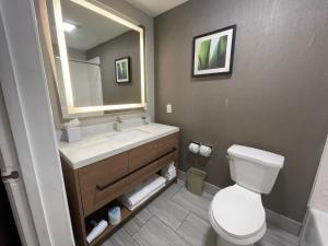 a bathroom with a toilet and a sink and a mirror at Grewal Hotel in Modesto +11 photos