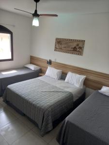 une chambre avec deux lits et un ventilateur de plafond dans l'établissement Pousada Parque Suites- Estacionamento e Piscina na enseada, à Guarujá