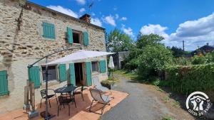 een patio met stoelen en een parasol naast een gebouw bij Guyor in Le Bez +6 foto's