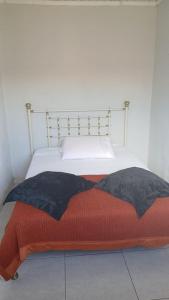 a bed with an orange and black blanket on it at Residencial Daitx in Capão da Canoa
