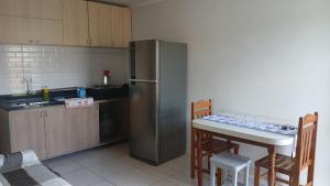 a kitchen with a table and a stainless steel refrigerator at Residencial Daitx in Capão da Canoa