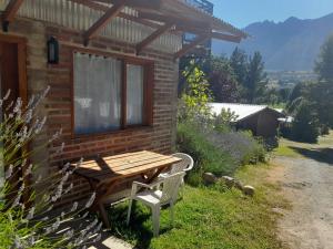 a wooden table and a bench next to a brick building at Apartamento Zorzal in Lago Puelo