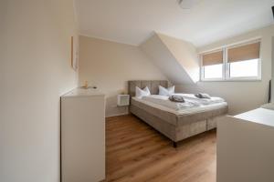a white bedroom with a bed and a window at Haus Lindolino in Elsterheide
