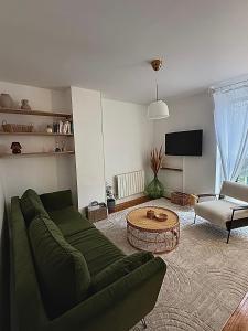 a living room with a green couch and a table at Appartement cocooning proche de lille in Loos