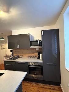 a kitchen with a black refrigerator and a stove at Appartement cocooning proche de lille in Loos +3 photos