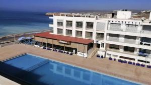 a hotel with a swimming pool next to the ocean at Sea & Pool View Apt 1 in Aourir