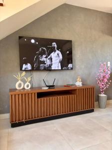 a living room with a television on a wall at 2 QUARTOS, Condomínio Villa de Rodes IMBASSAÍ Super bem localizado, Próximo a PRAIA, FARMÁCIAS, MERCADO E RESTAURANTES in Imbassai