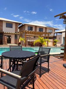 a patio with a table and chairs next to a pool at 2 QUARTOS, Condomínio Villa de Rodes IMBASSAÍ Super bem localizado, Próximo a PRAIA, FARMÁCIAS, MERCADO E RESTAURANTES in Imbassai