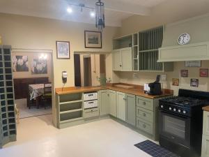 une cuisine avec des armoires blanches et un four à plaques de cuisson dans l'établissement Villa Olivia, à Riebeek-Kasteel 25 autres photos