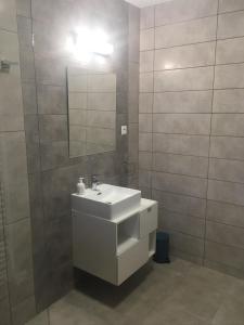 ein Badezimmer mit einem weißen Waschbecken und einem Spiegel in der Unterkunft Apartmány Zuberec 893 in Zuberec + 9 Fotos