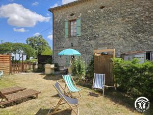 a house with two chairs and a bench and an umbrella at Roumanieu le gite in Saint-Gauzens