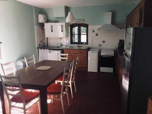 een keuken met een tafel, stoelen en een koelkast bij Ancienne ecole de moncere in Penne