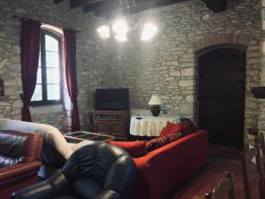 een woonkamer met een bank en een stenen muur bij Ancienne ecole de moncere in Penne