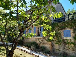 een oud stenen huis met een boom ervoor bij Ancienne ecole de moncere in Penne