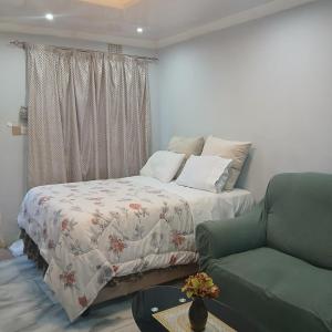 a bedroom with a bed and a couch and a chair at Carlcyn 263 Cottage in Bulawayo