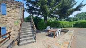 a stone building with a wooden table and a staircase at La castagnal in Jouqueviel +5 photos