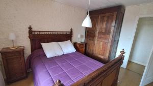 a bedroom with a bed with a purple comforter at La castagnal in Jouqueviel