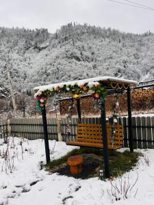 een houten bank met een prieel in de sneeuw bij Woodlandia Resort Borjomi in Borjomi