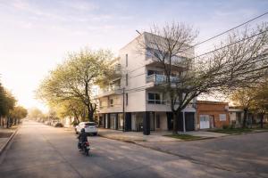 a man riding a motorcycle down a street next to a building at Río Breve - Departamento moderno en Zona Norte in Rosario