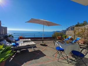 un patio avec une table, des chaises et un parasol dans l'établissement Casa del Corriere, à Positano