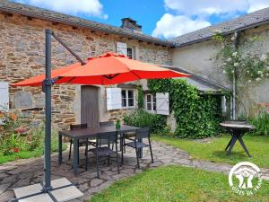 a table with a red umbrella in front of a house at Calouze in Gijounet