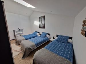 two beds in a room with blue sheets at Gite Bergamote in Champenoux
