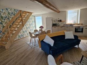 a living room with a blue couch and a kitchen at Gite Bergamote in Champenoux