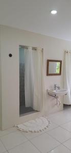 een witte badkamer met douche en wastafel bij Windy Hill Suites in Bacolet