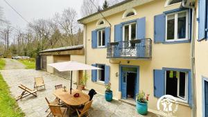 een terras met een tafel met een parasol en een huis bij Le moulin de cameliere in Caudebronde