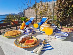 une table avec un petit-déjeuner composé de pain et de jus d'orange dans l'établissement Casa del Corriere, à Positano