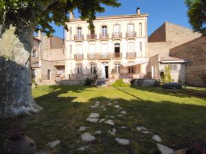 een groot gebouw met een boom ervoor bij La maison bachelet in Claira