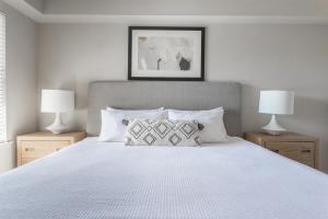 een slaapkamer met een wit bed met twee lampen bij Landing Stylish 1BD Courtyard Pool in Broken Arrow +34 foto's