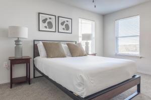 een slaapkamer met een groot bed met witte lakens en kussens bij Landing Apartments - Redbud Ranch in Broken Arrow +20 foto's