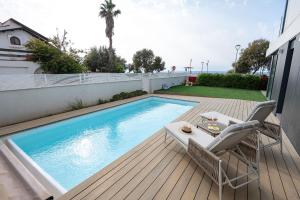 a swimming pool with two chairs and a table on a deck at Myk Beach Nahariya in Nahariyya