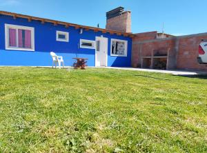 een blauw huis met een tafel en een stoel in een tuin bij wind house - casa del viento in Perito Moreno